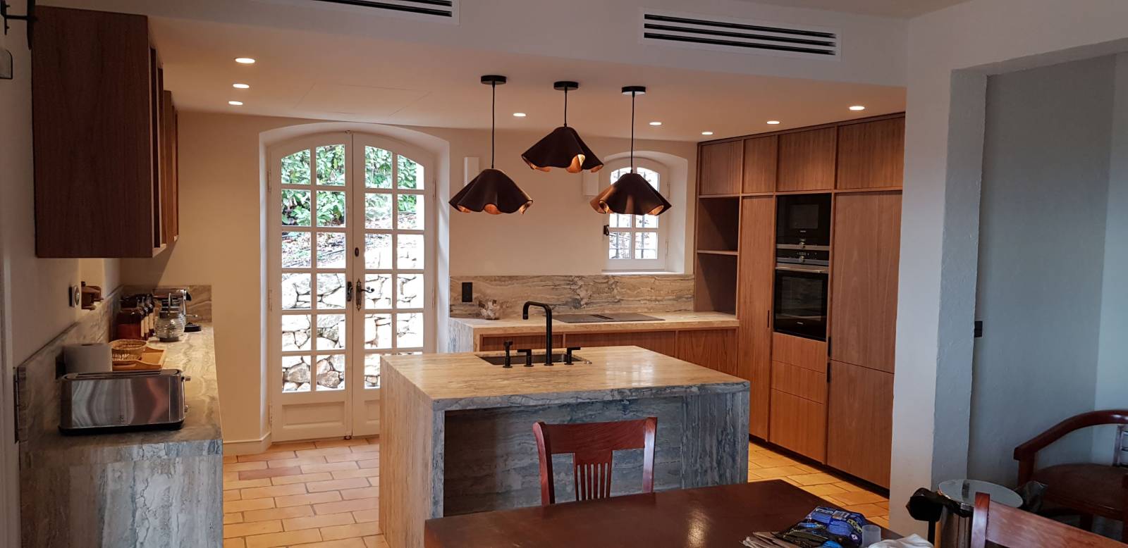 cuisine sur mesure avec un ilot central en mélaminé noir pour les caissons de cuisine, et habillée avec des façades en placage Noyer US